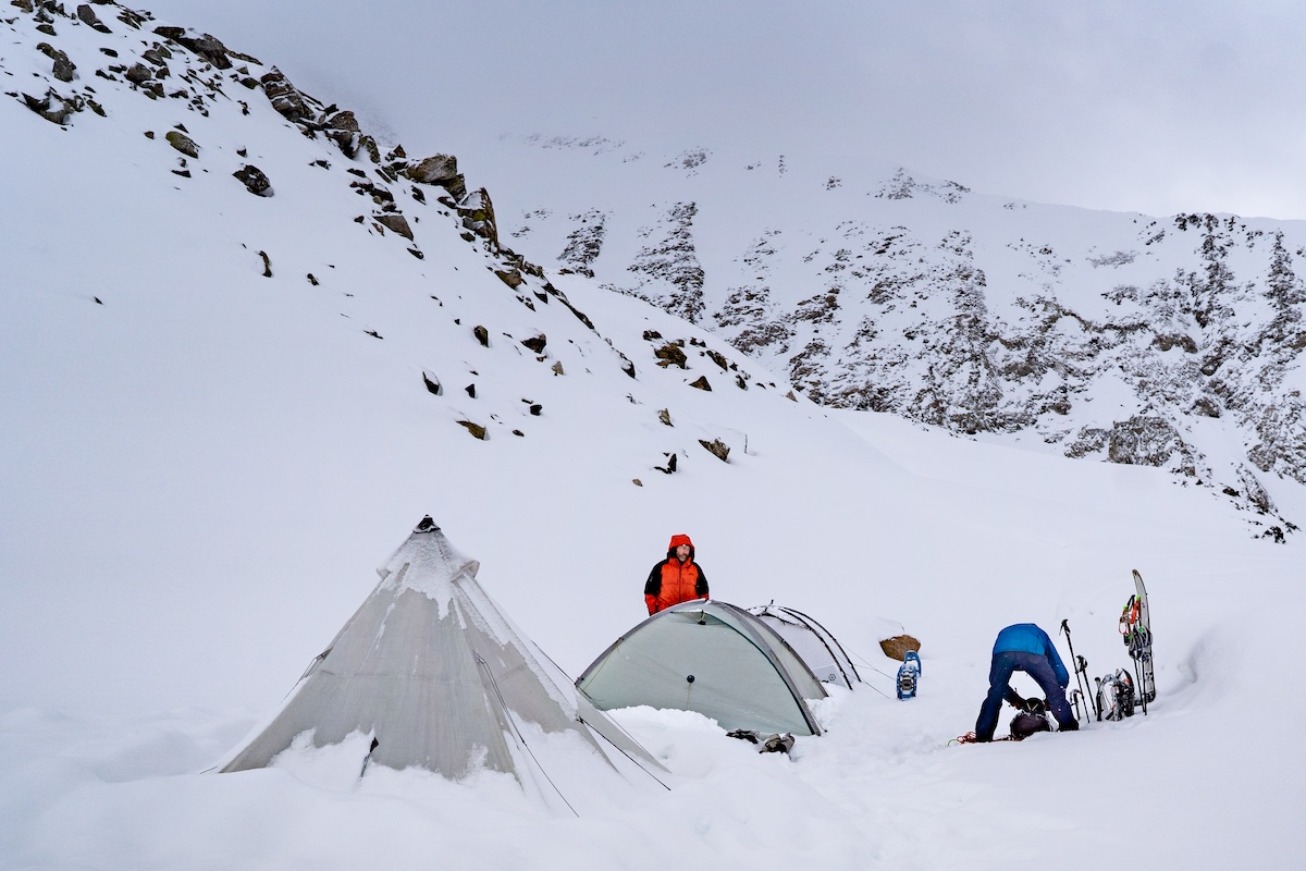 Skiers and snowshoers set up tents in deep snow