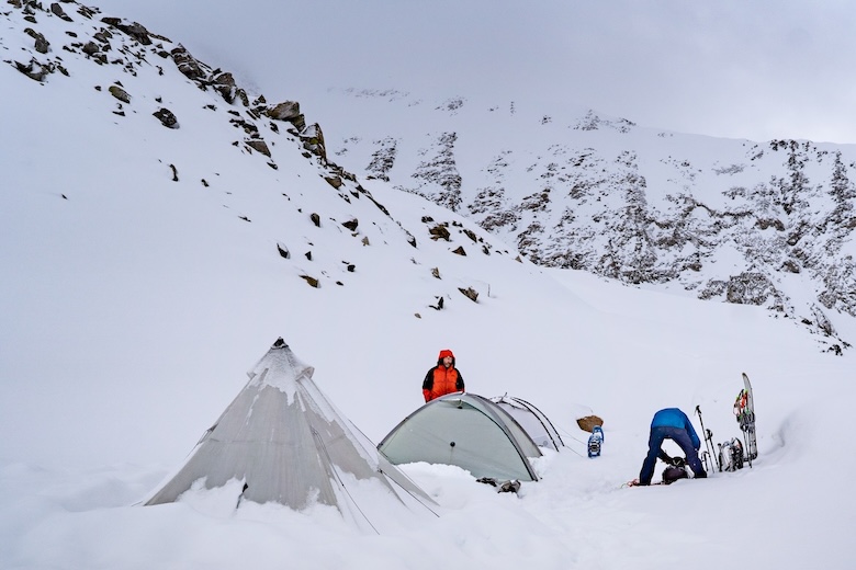 Skiers and snowshoers set up tents in deep snow