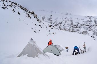 Skiers and snowshoers set up tents in deep snow