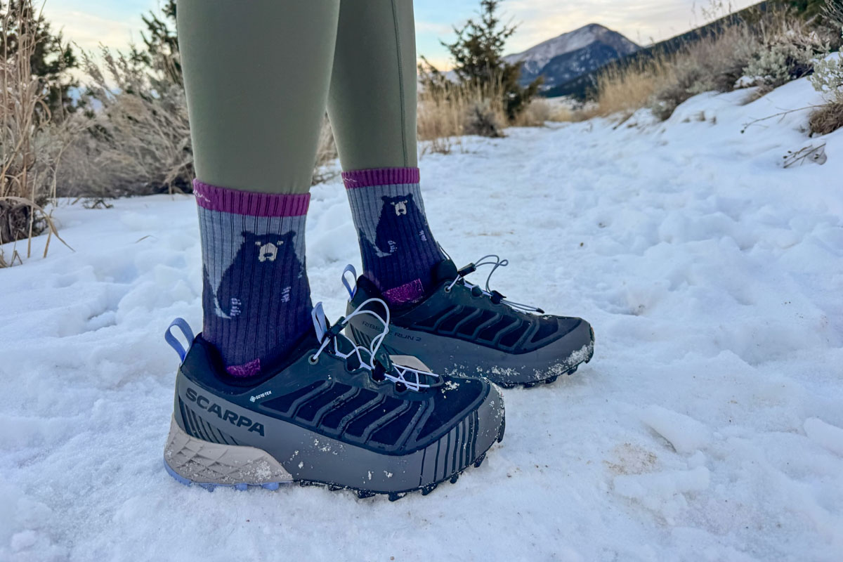 A closeup shot of a pair of Scarpa shoes standing in the snow