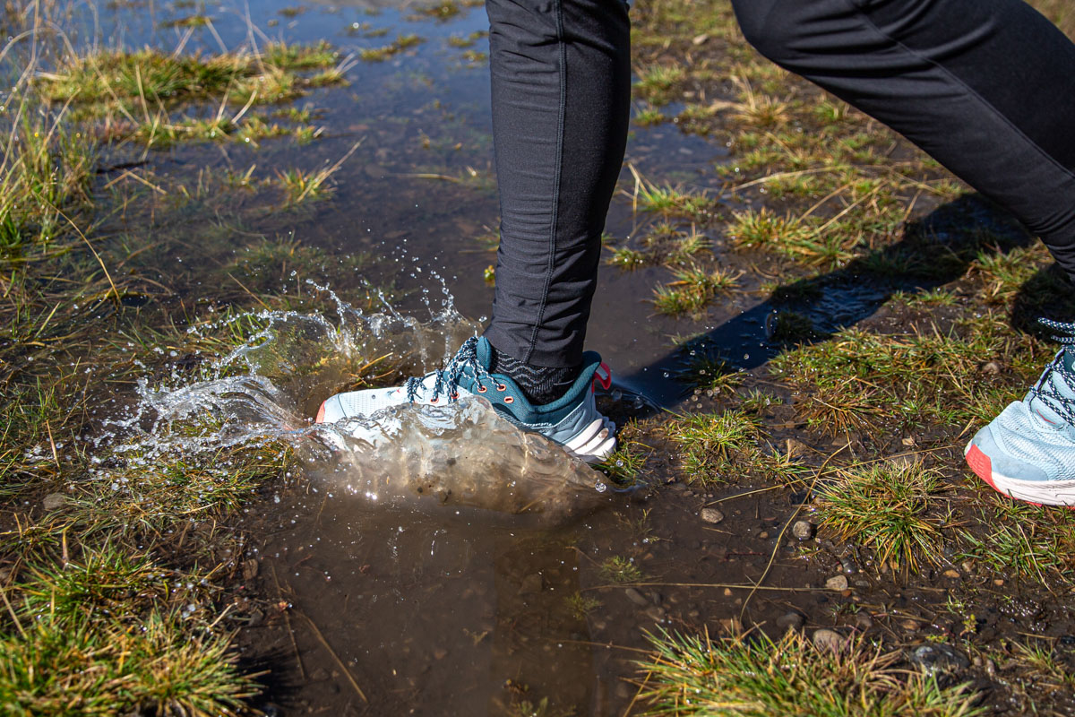 A hiking shoe walking through a puddle