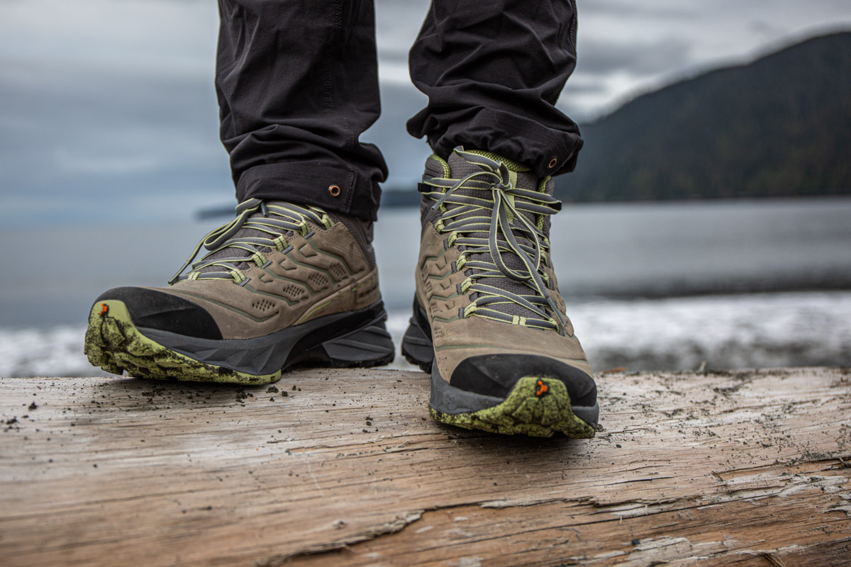 A pair of brown and green waterproof hiking boots on a log