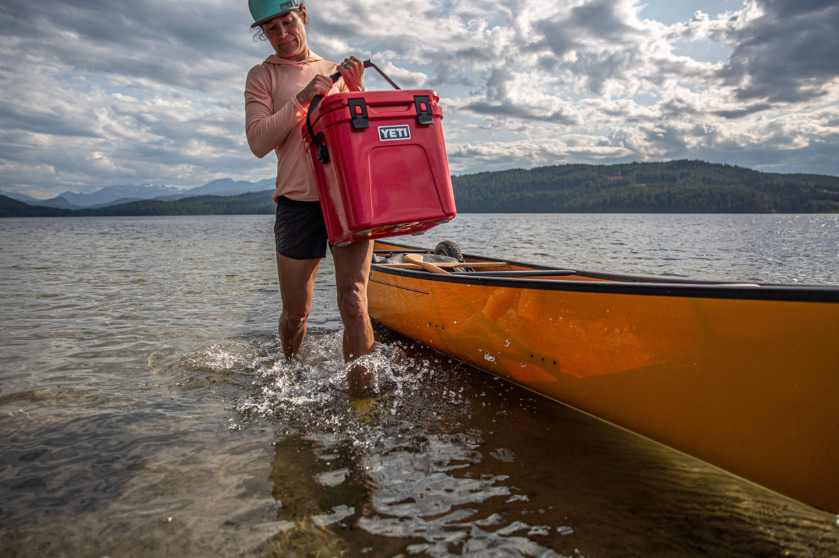 A woman hauling a cooler out of a canoe