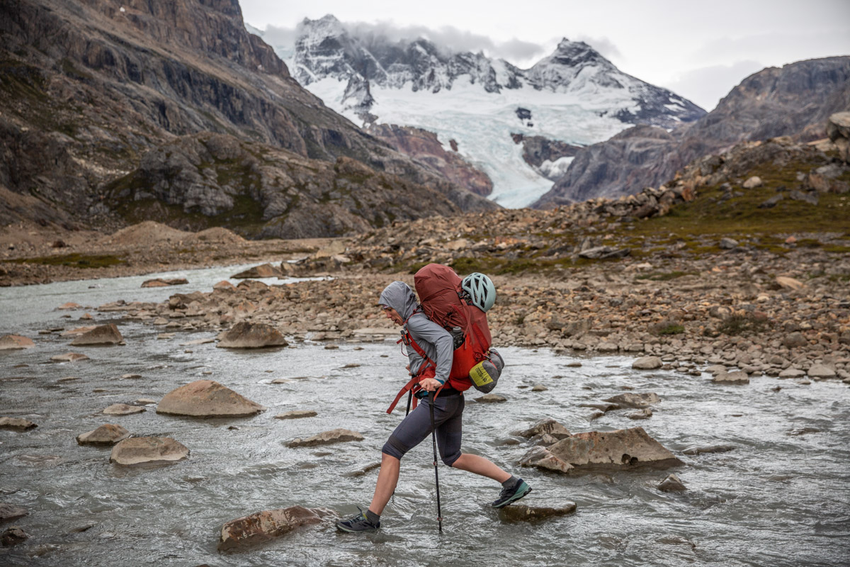 A woman hiking across a stream.