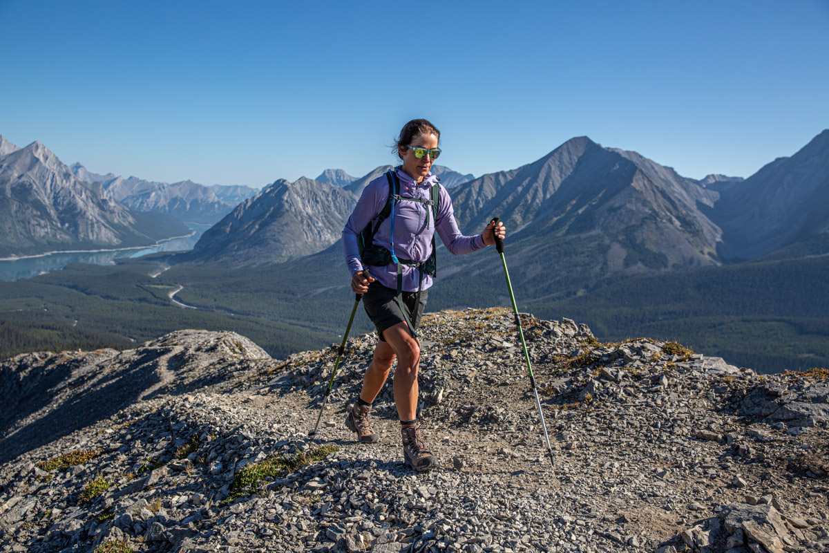 A woman hiking on a ridge wearing a purple windbreaker