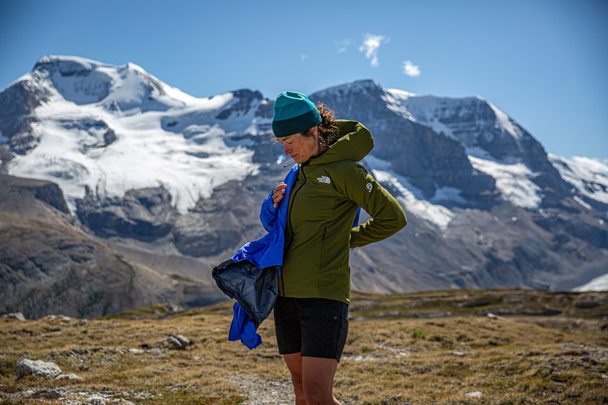 A woman pulling a shell on over her synthetic jacket