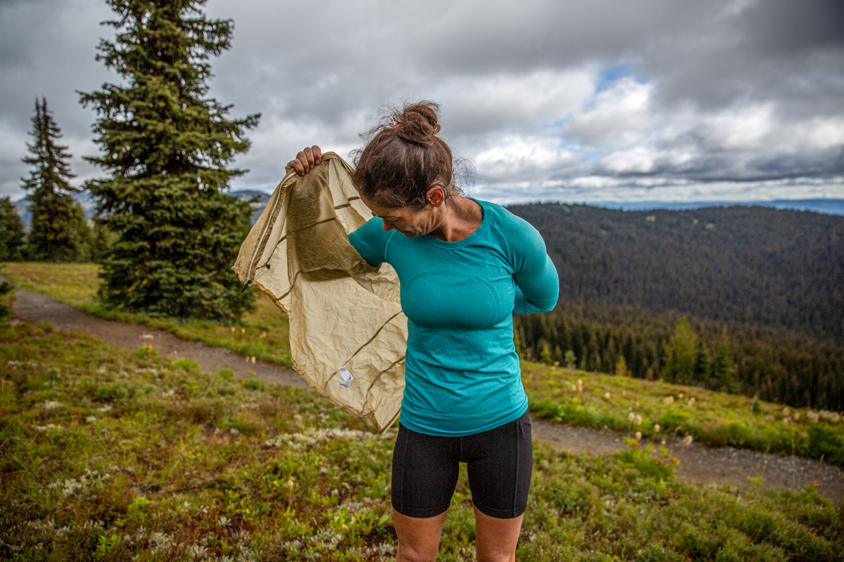 A woman pulling on a windbreaker jacket