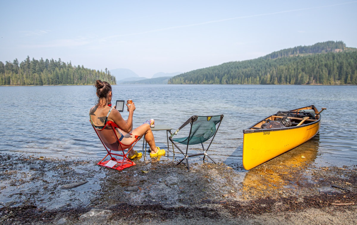 A woman relaxing at a river wearing camp shoes