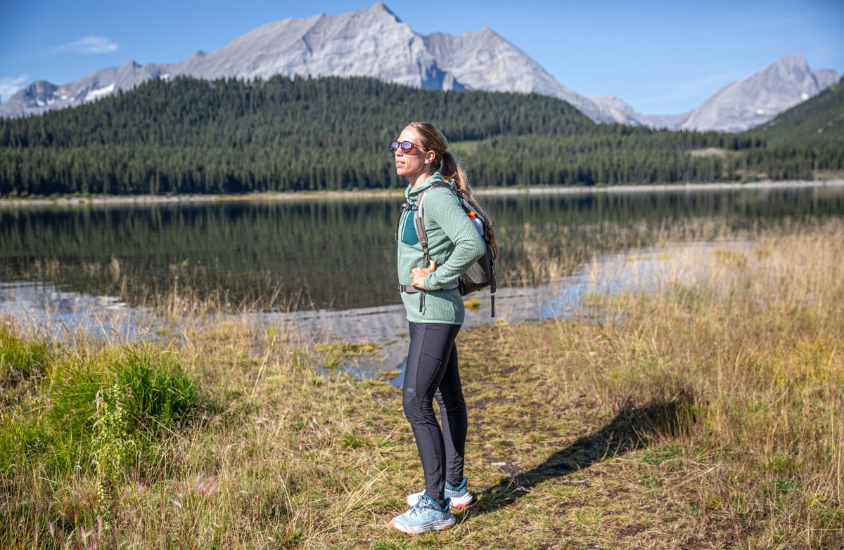 A woman standing near a lake in waterproof hiking shoes.
