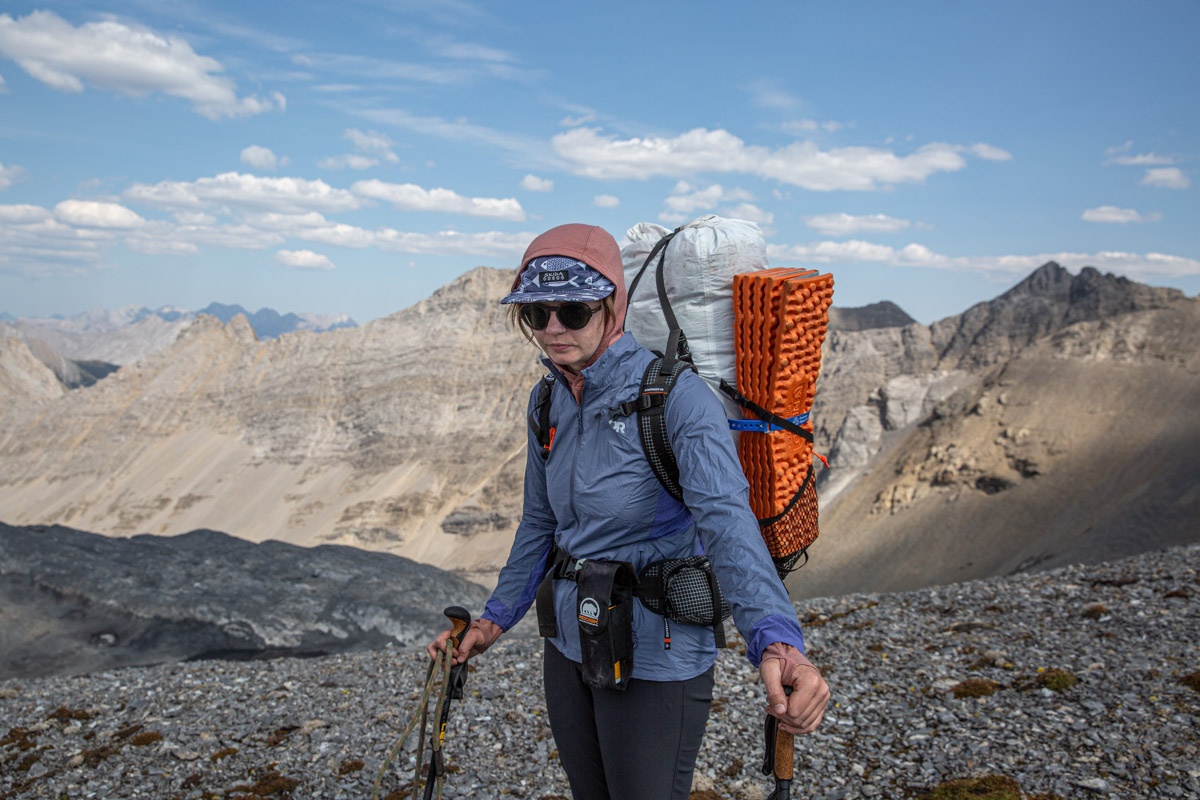 A woman standing on a ridge wearing a blue windbreaker