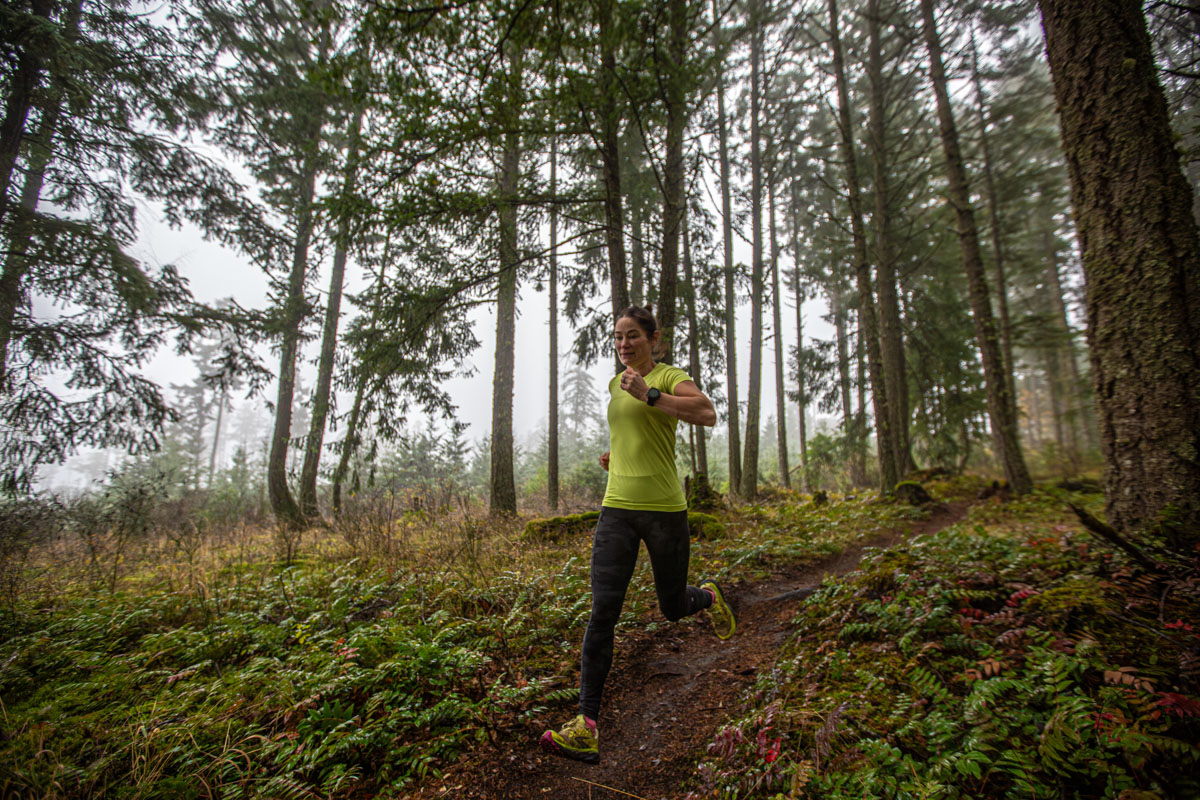 A woman trail running wearing a GPS watch
