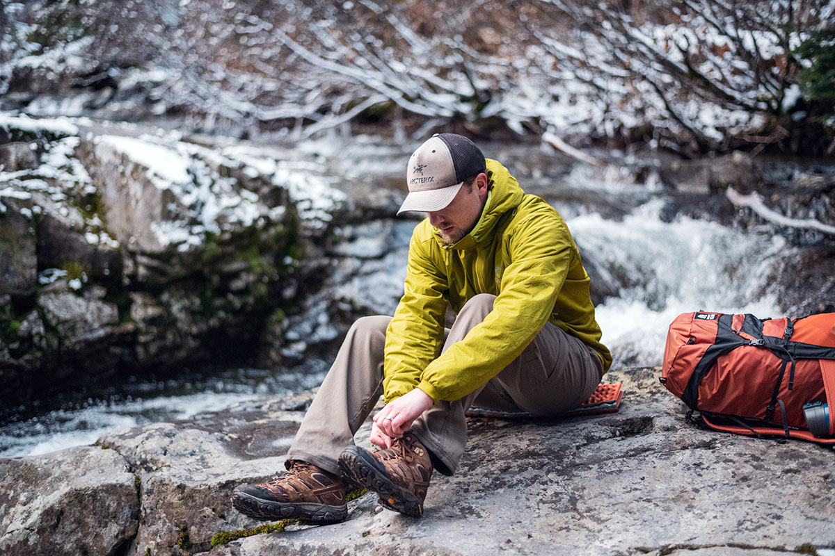 A man laces up his boots while wearing the Arc'teryx Atom LT Hoody