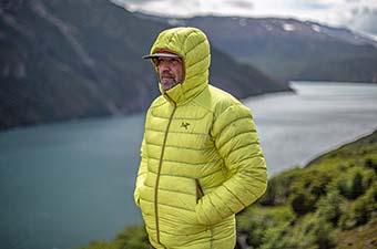 A man standing above lake in Patagonia wearing a yellow down jacket