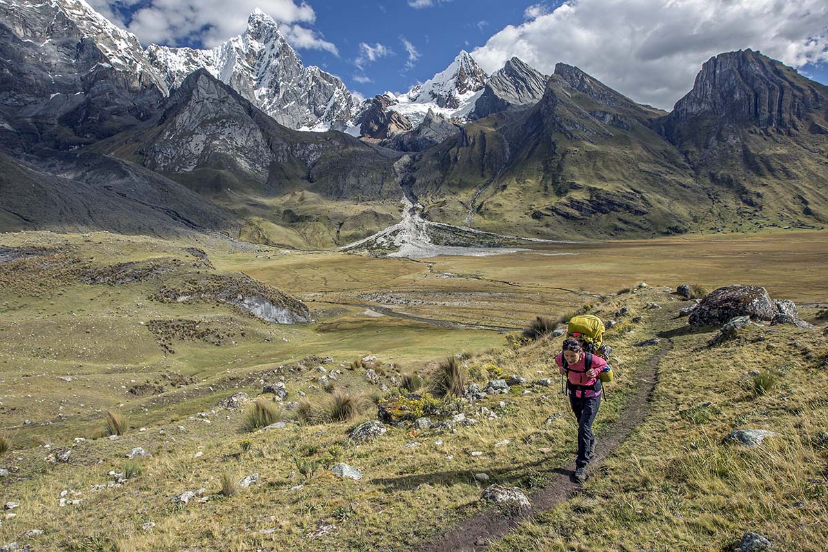 a woman is shown backpacking in mountains