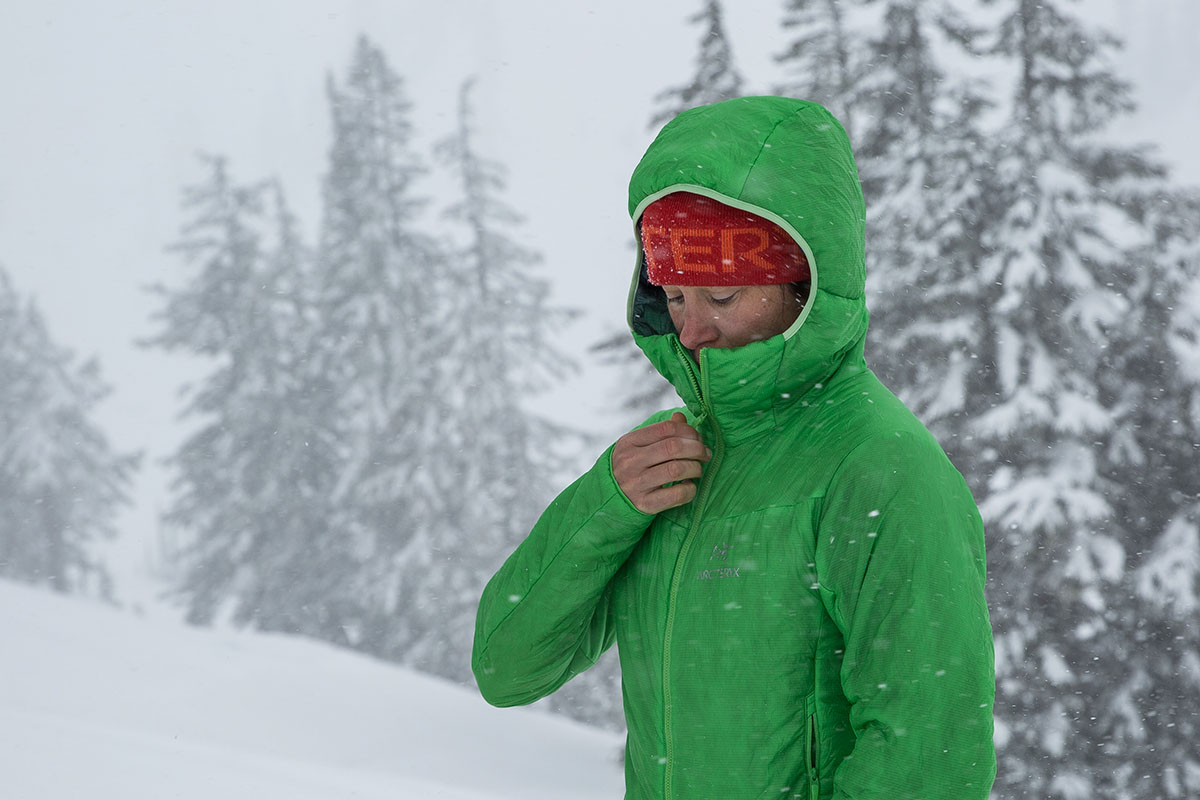 A woman zipping up a synthetic jacket in the snow