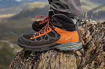 A close up of someone standing on a rock wearing the Asolo Falcon Evo GV hiking boots