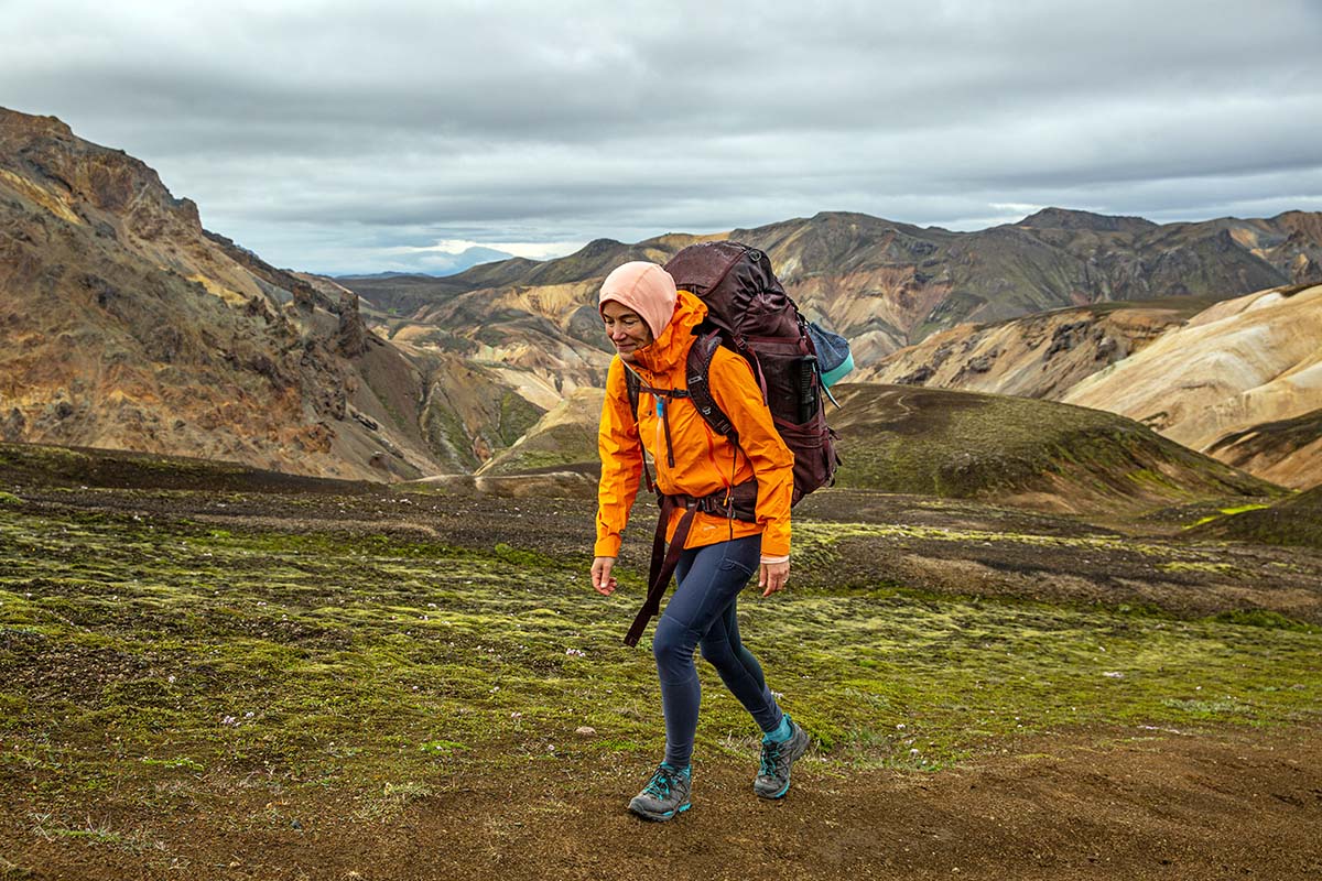 A woman traverses a green field while backpacking in Norway.