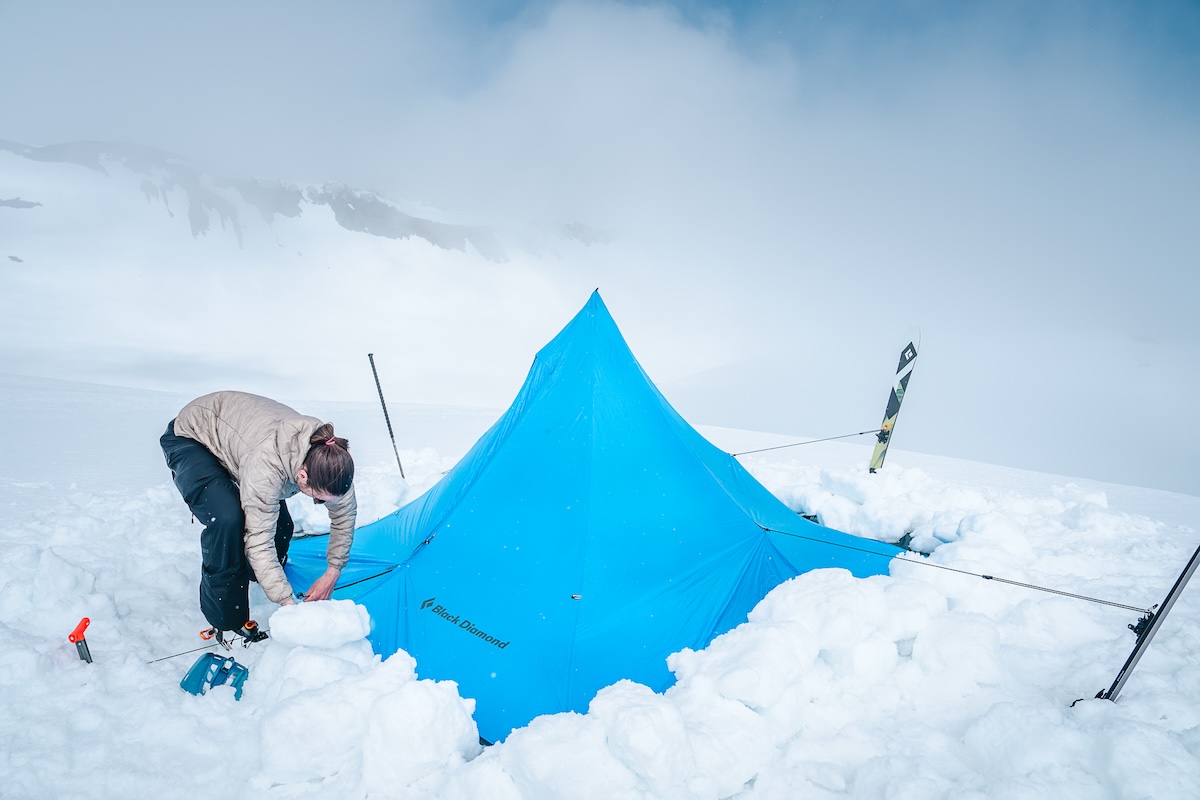 A man pitching a tent in snow