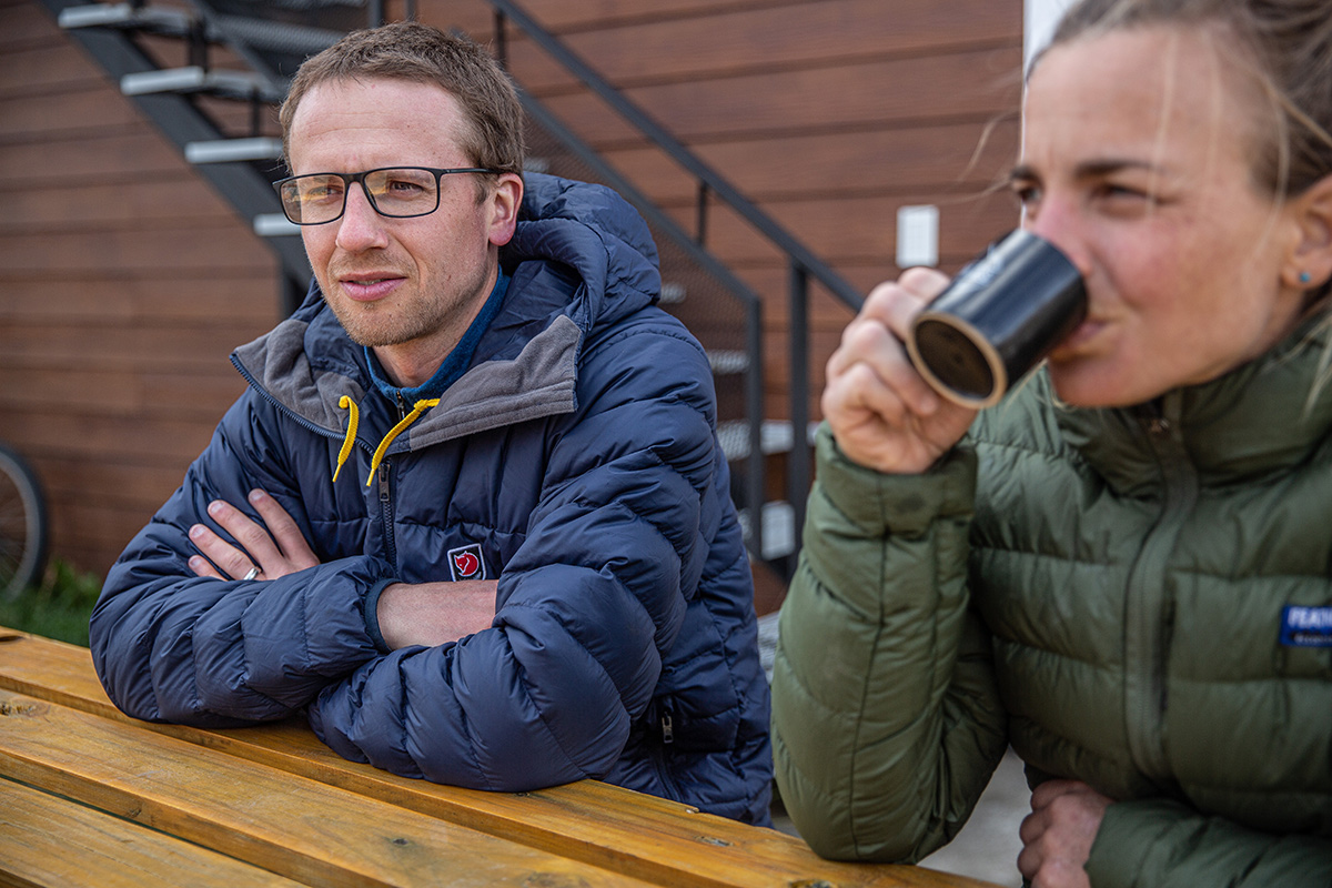 A pair of hikers in their fjallraven jackets take a break at a picnic table.