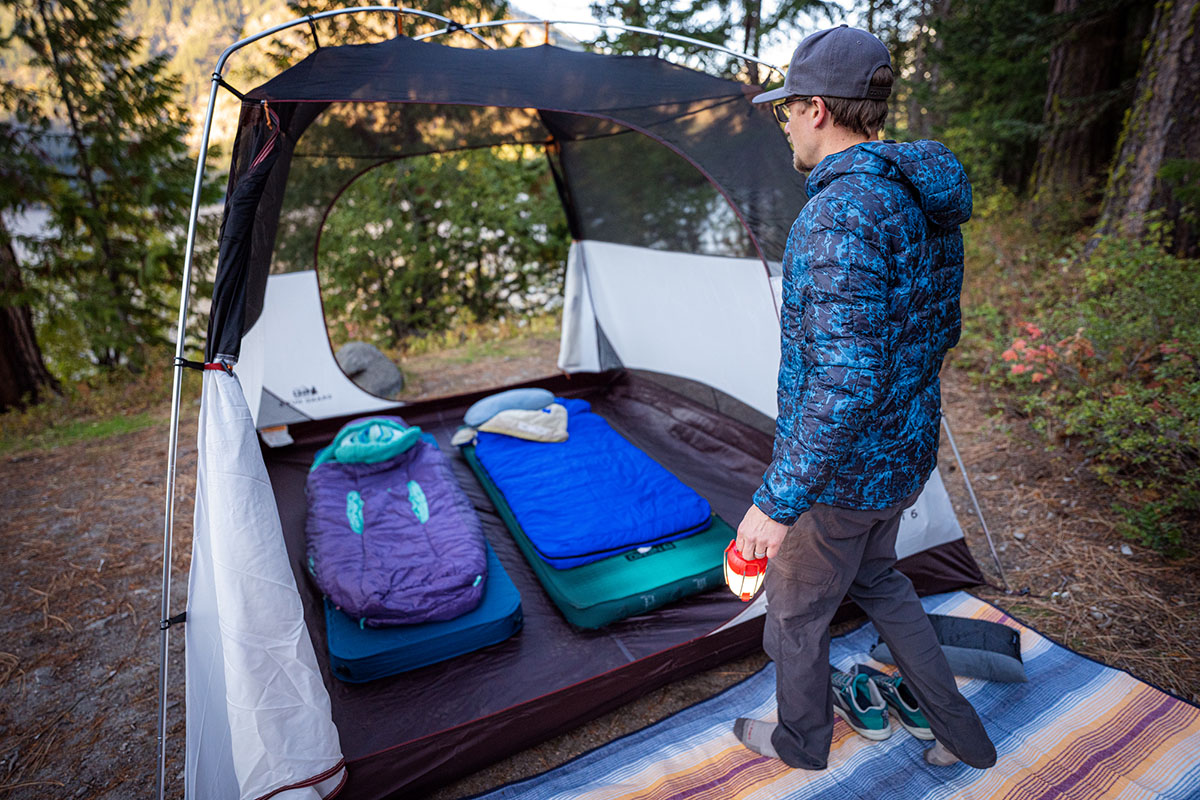 A man sets up his camping tent in the forest.