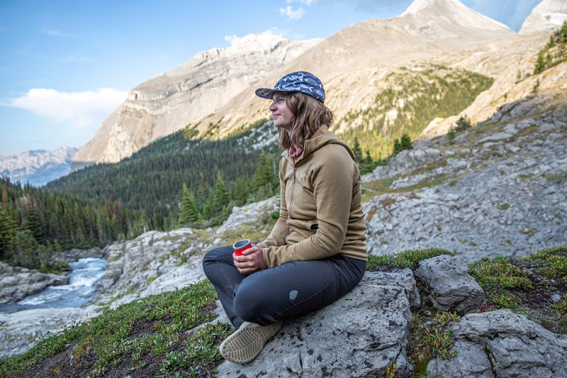 a woman sitting on a rock in the mountains