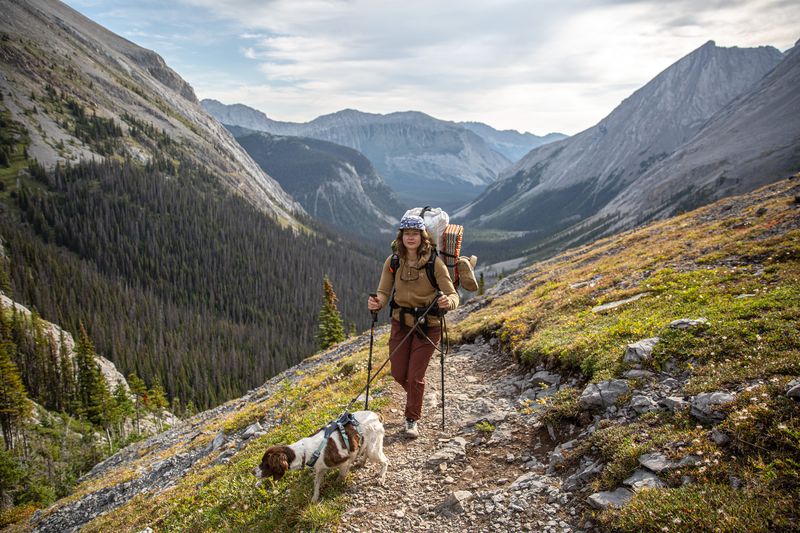 a woman hikes toward the camera in the sun