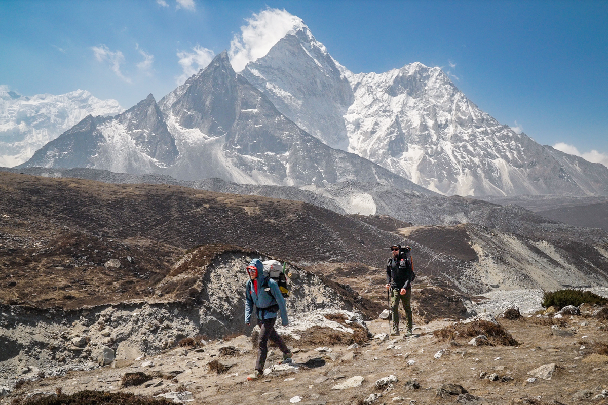 Two men hiking in front of mountains in Nepal