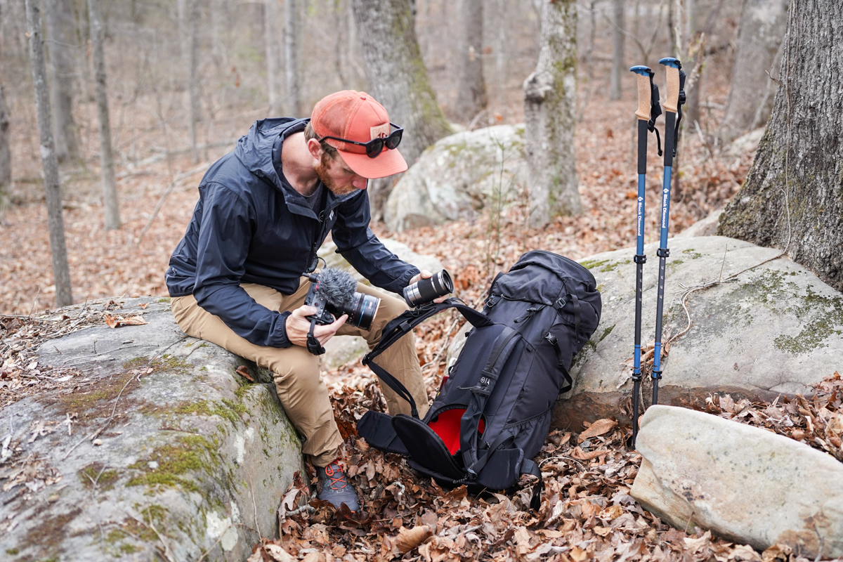 A man takes lenses out of a camera backpack