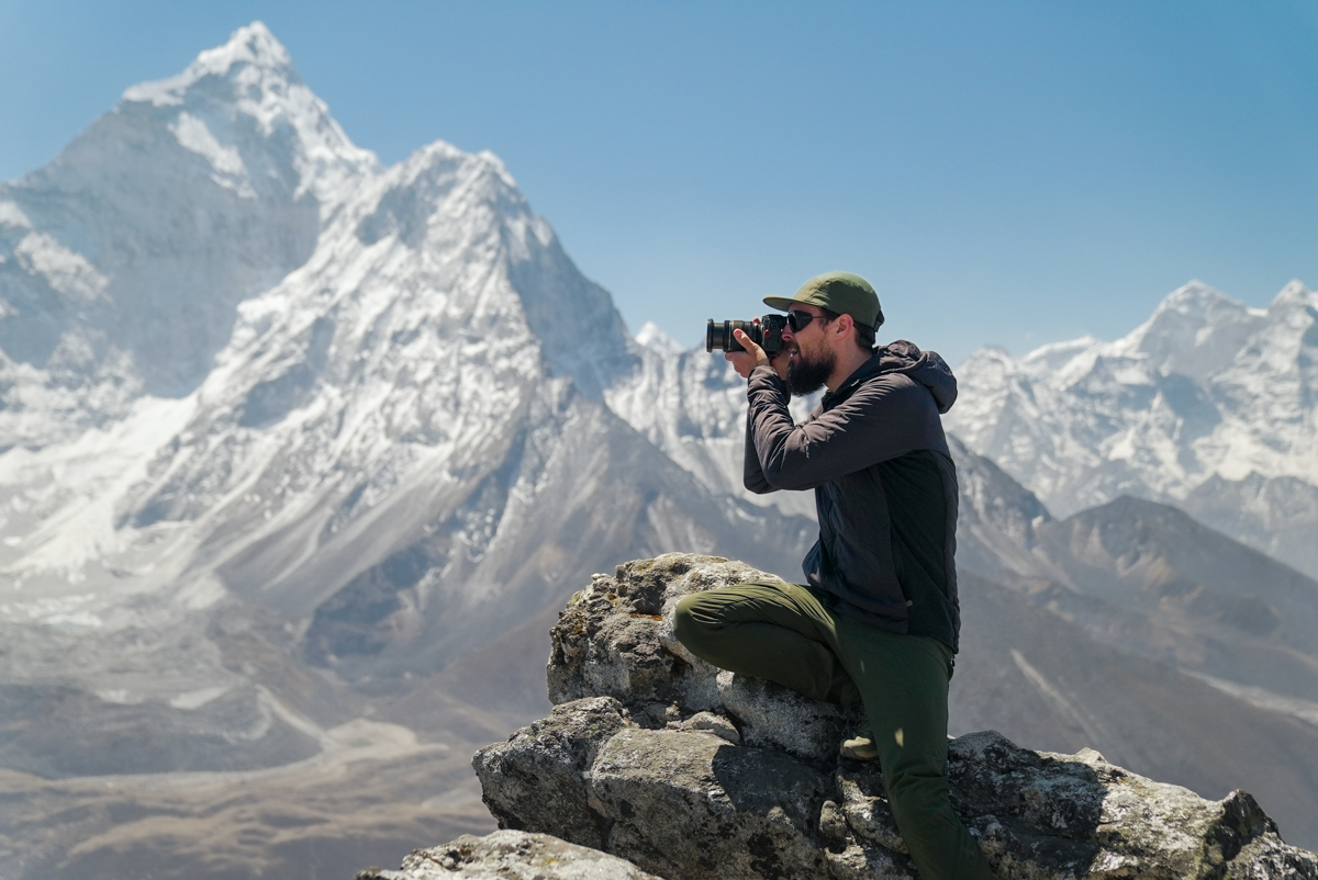 A man taking a photo in front of mountains