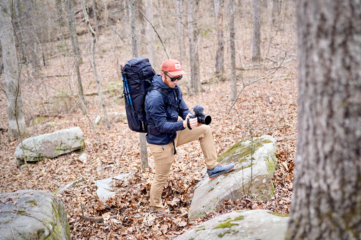 A man filming while wearing a backpack