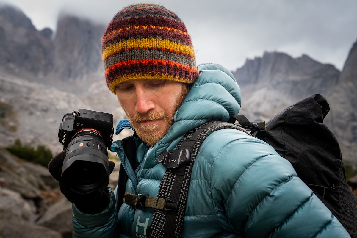 A man putting his camera on his shoulder strap
