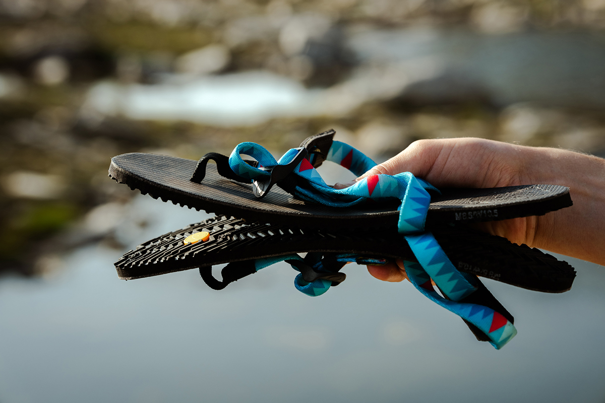 A hand holding two minimalist sandals