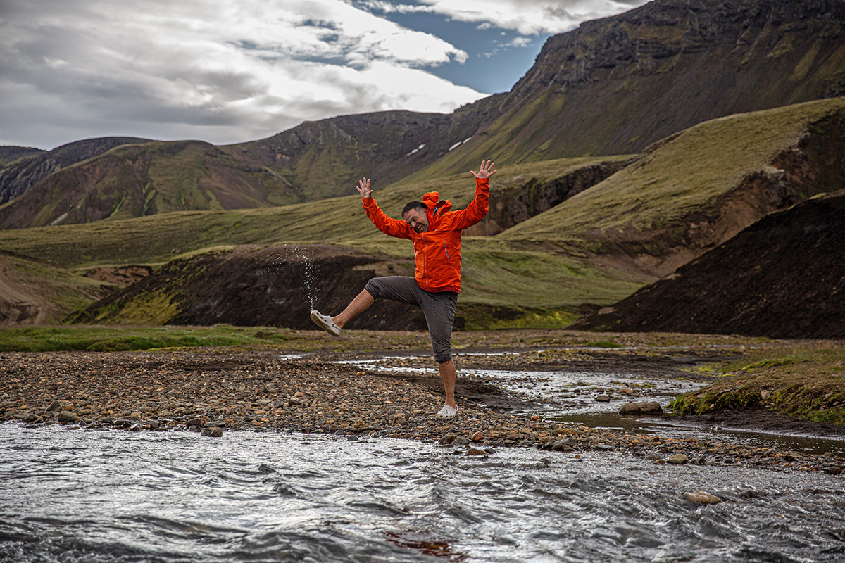 A man jumping in a river wearing camp shoes