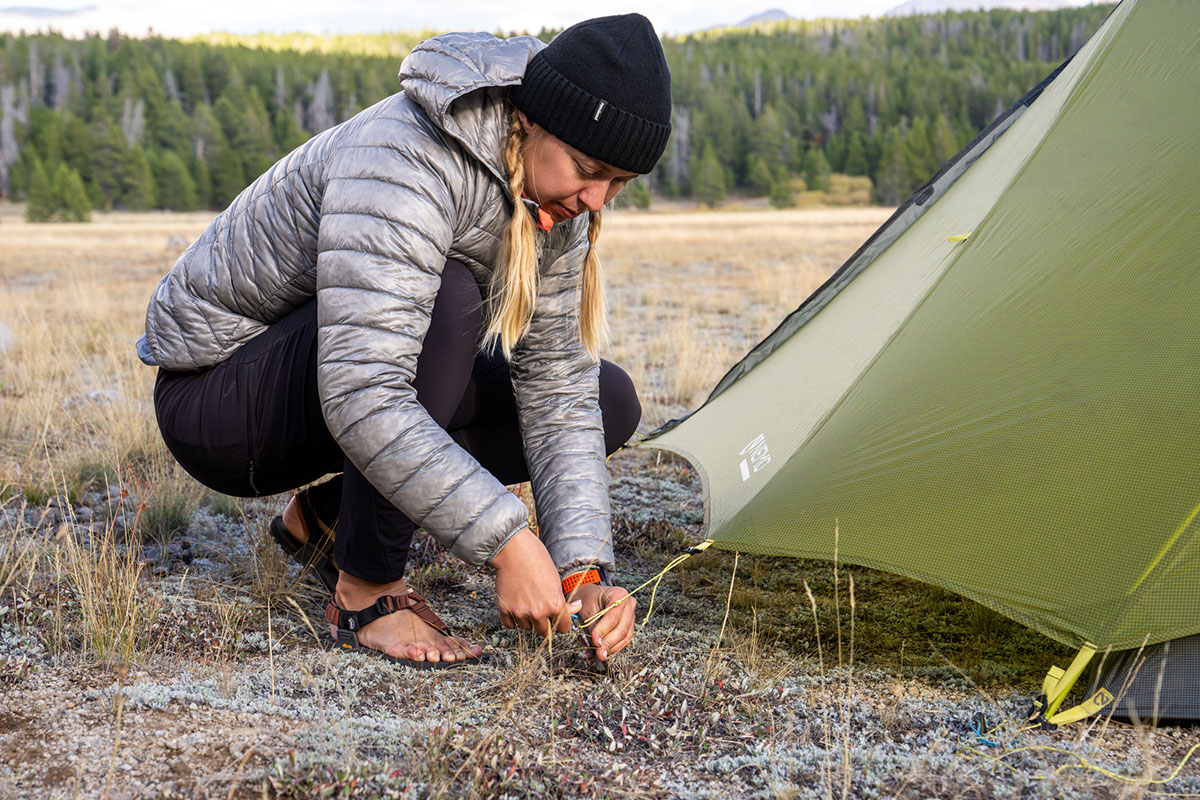 A woman pitching a tent in camp shoes