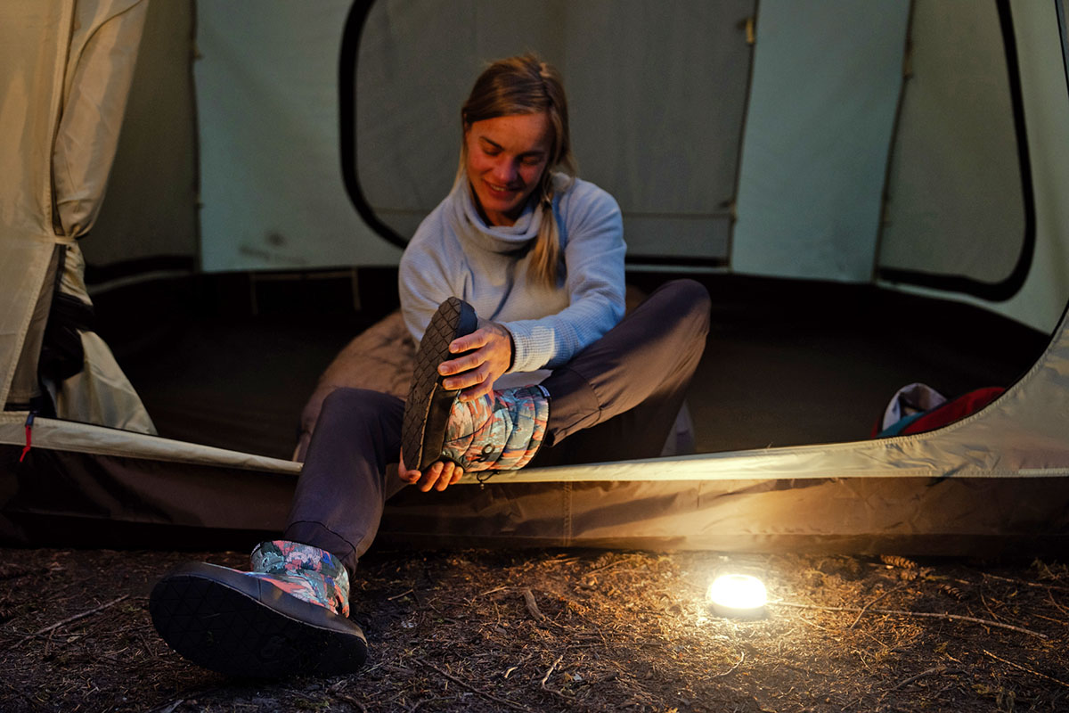 A woman taking off camp shoes in a tent