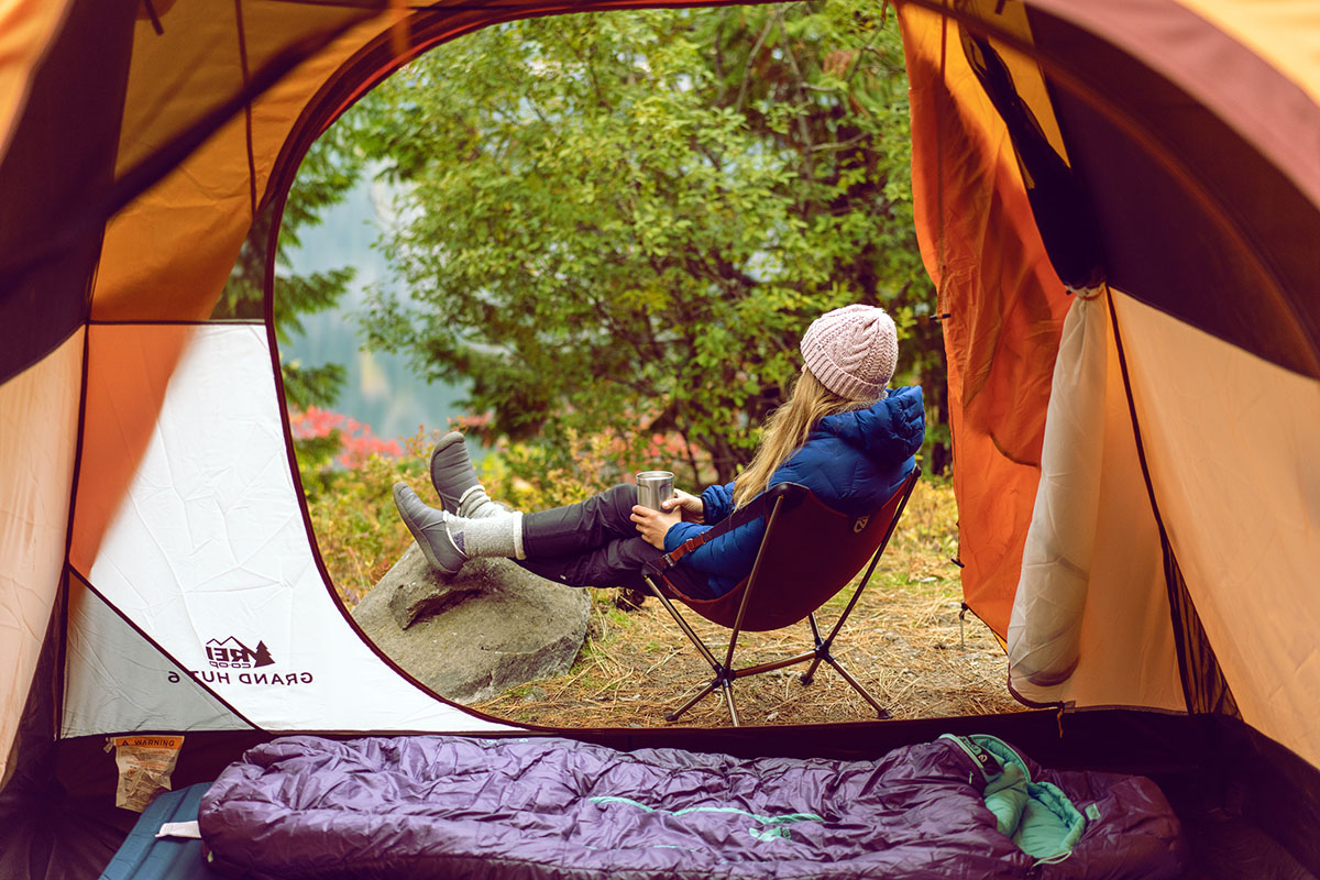 A woman relaxing outside of a tent in camp shoes