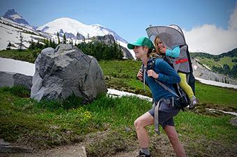A woman hiking near Mount Rainier with her child in a backpack