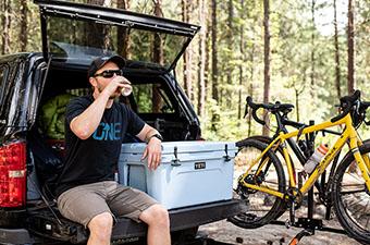 A man sits on a tailgate next to the Yeti Tundra