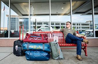 Sitting on bench at airport with group of duffel bags