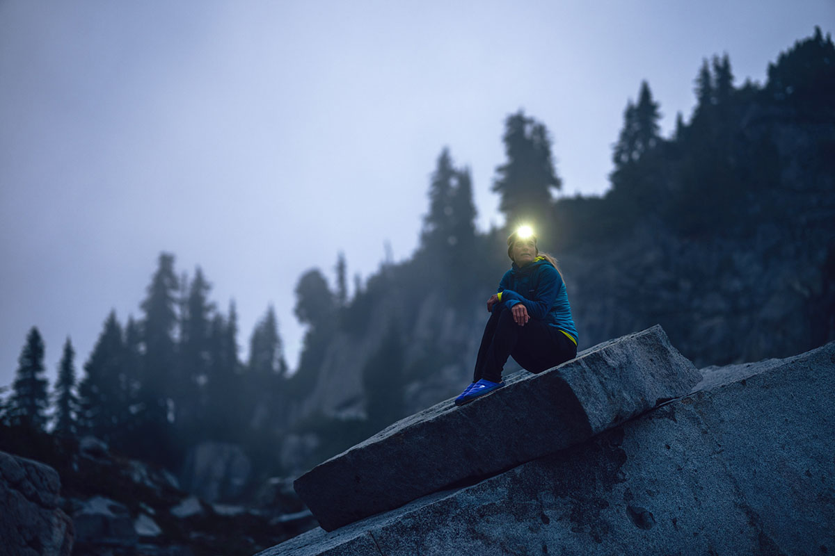 A woman sitting on a rock with a headlamp