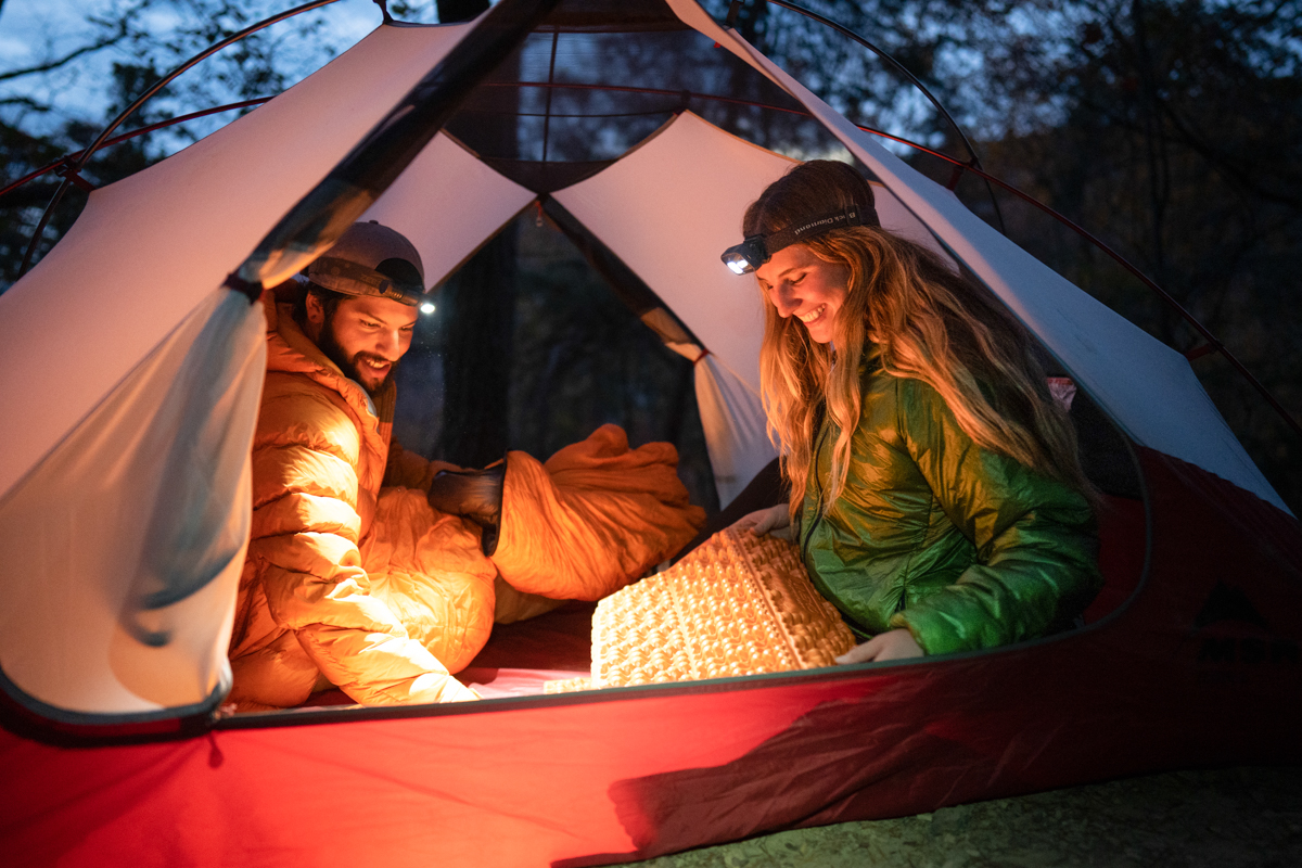 Two campers using headlamps in a tent