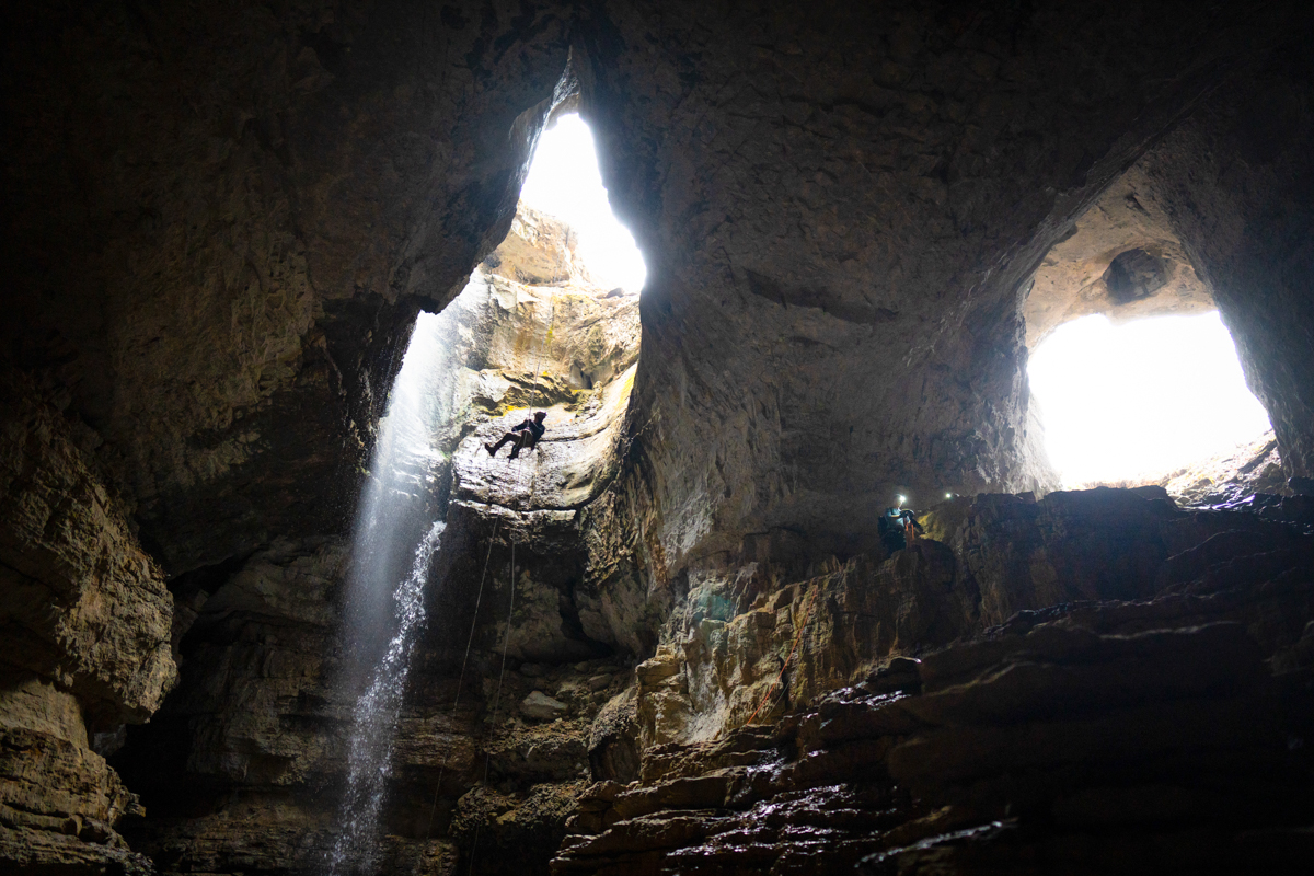 Cavers descending into a cave with headlamps