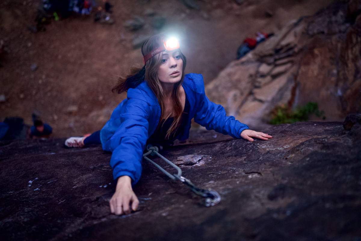 A woman climbing with a headlamp