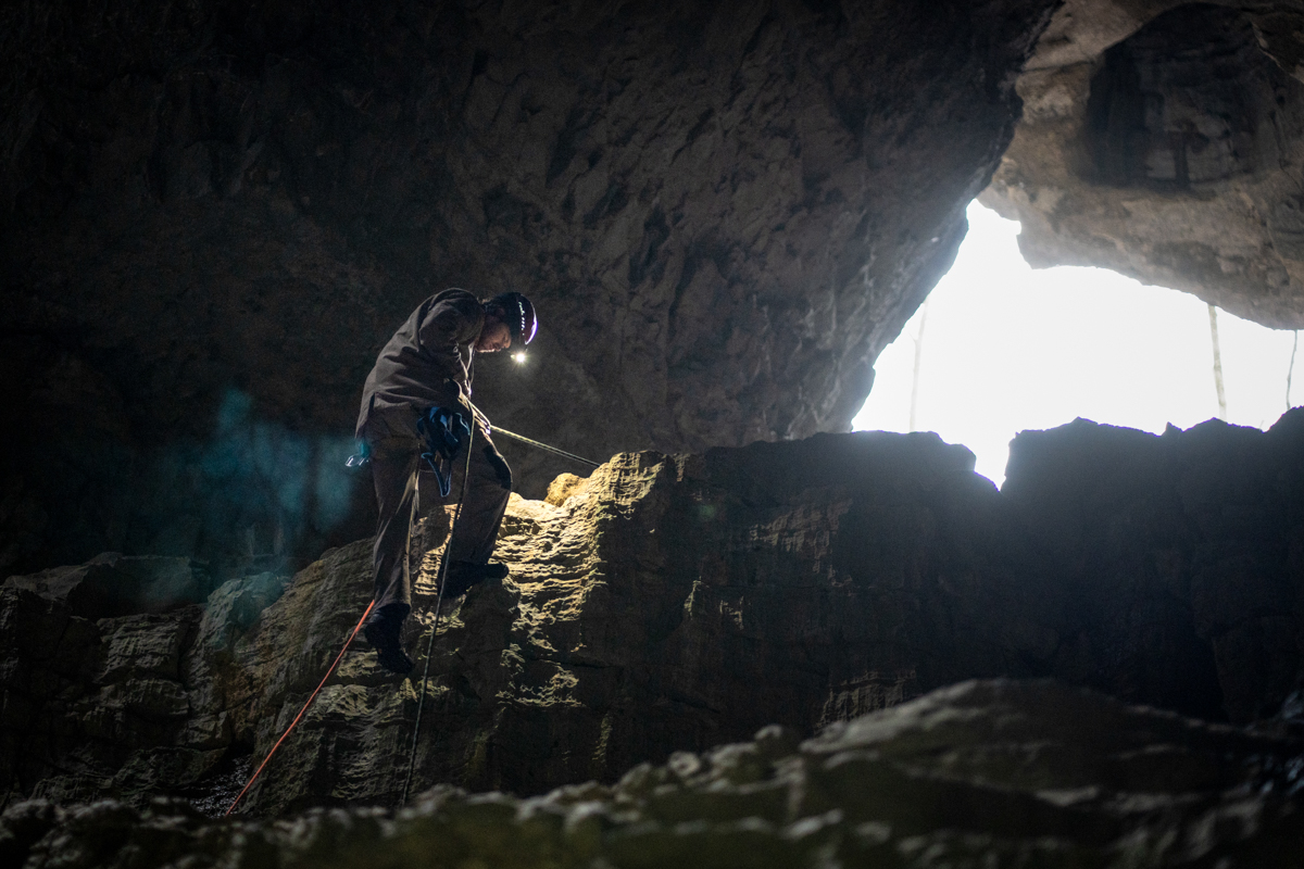 A man rappelling in a cave
