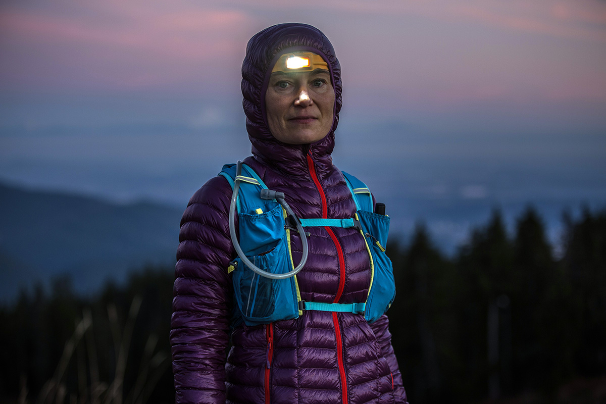 A woman with a headlamp and running vest