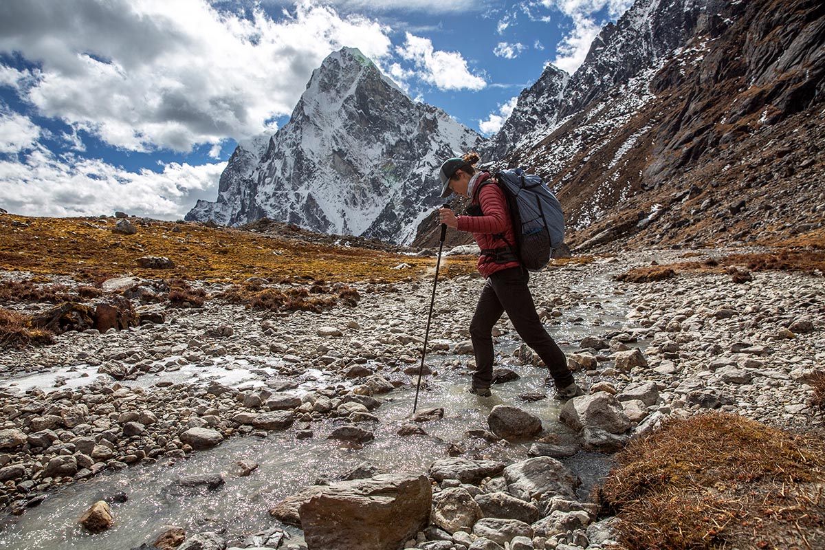A woman hiking through a stream in Nepal