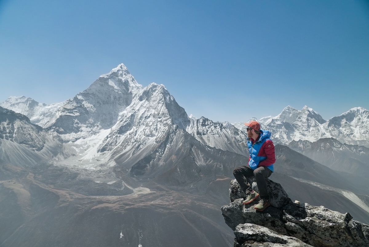 A hiker perches on a rock high in the mountains of Nepal.
