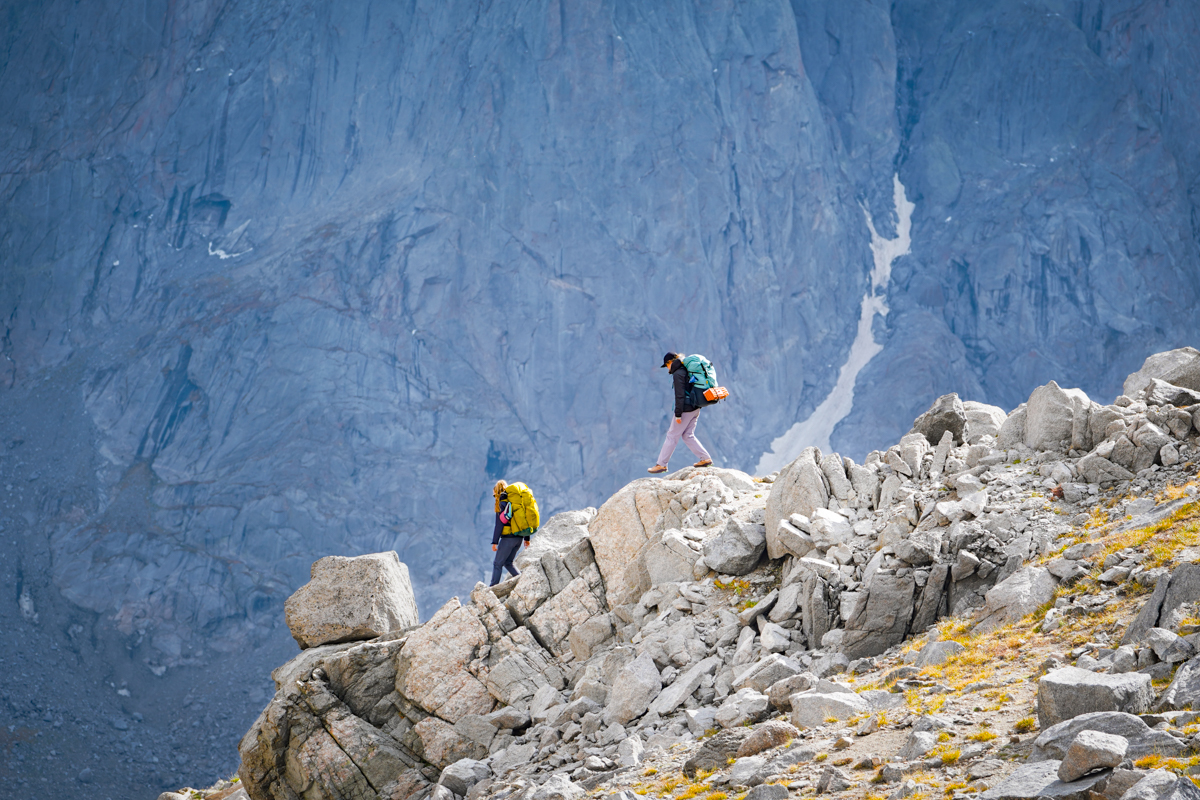 A pair of hiker scramble over rocks in the Wind River Range.