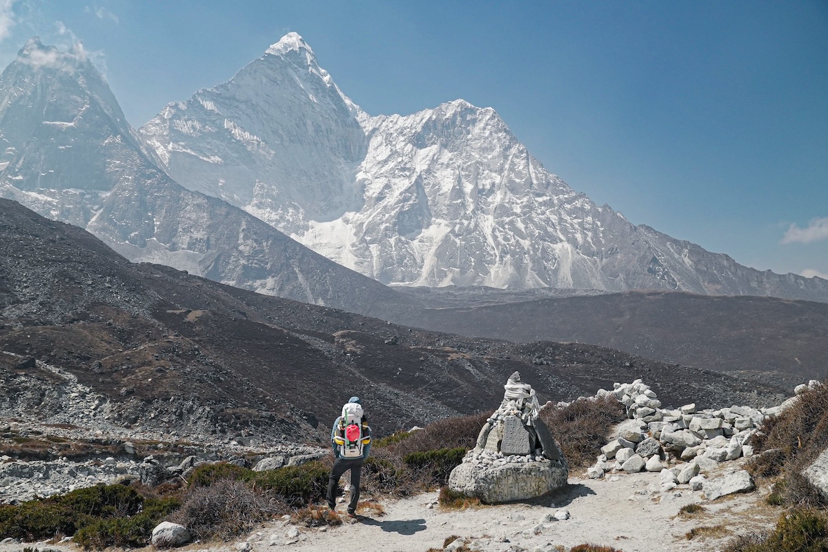 A hiker in Nepal rests at a rock outcropping.