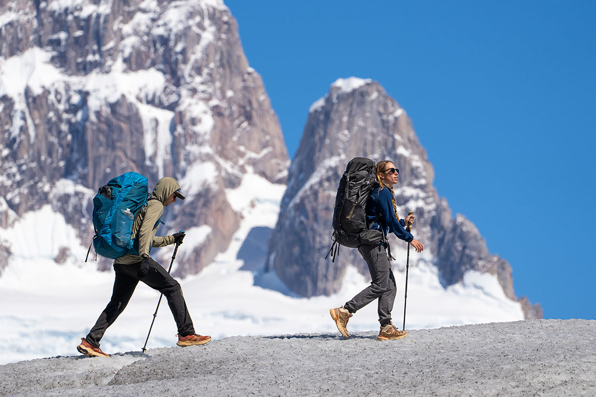 Two hiker traverse a glacier high in the snowy mountains.